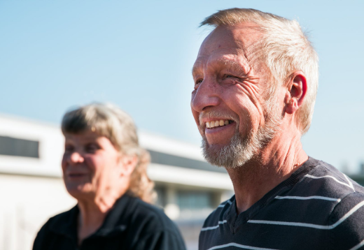Man och kvinna framför hus och blå himmel