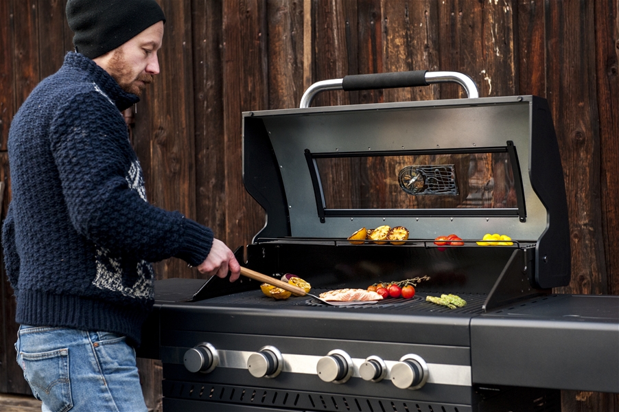Man grillar lax och grönsaker